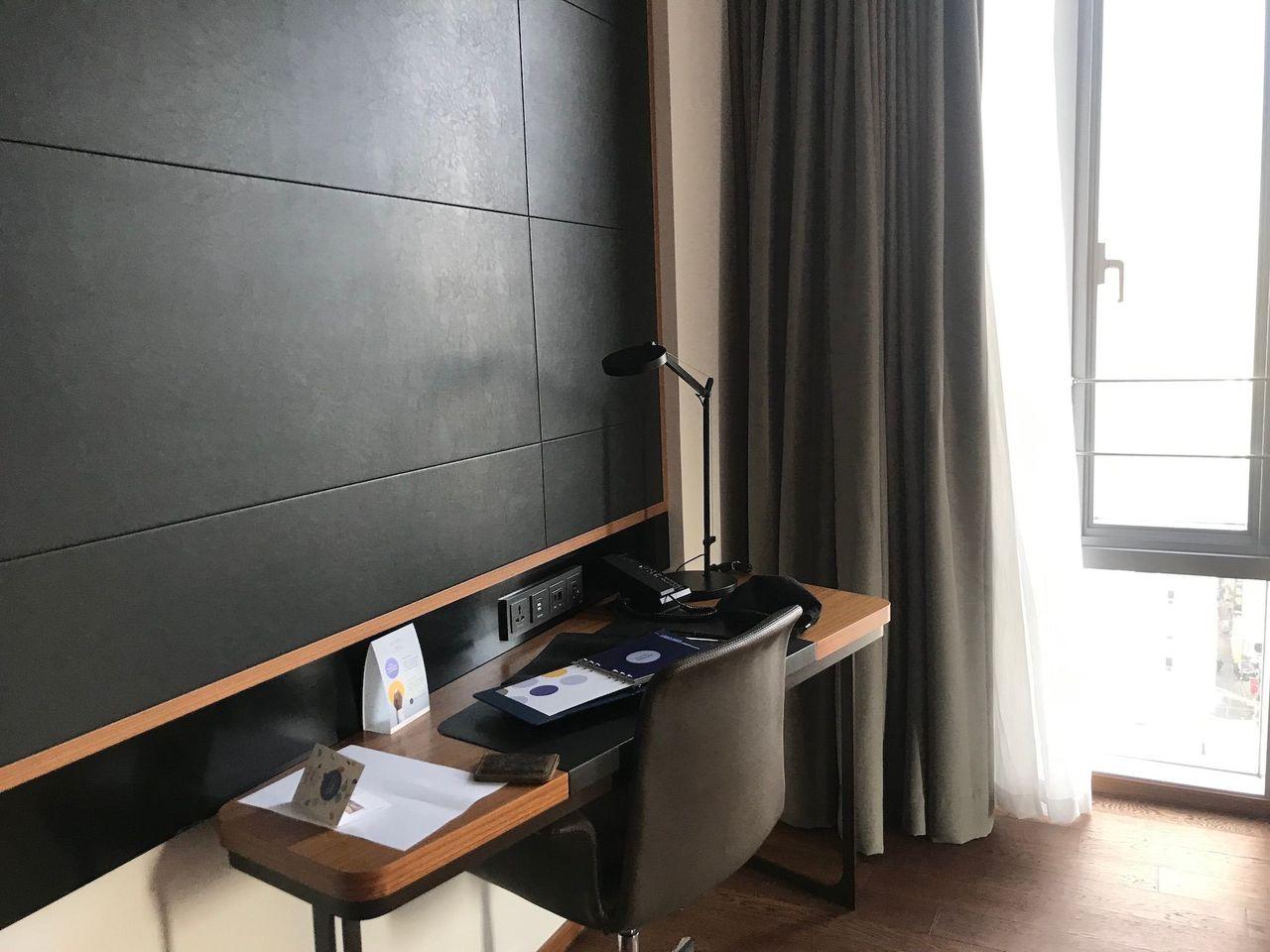 Modern workspace with a desk and chair next to a sunlit window in Dongdaemun Novotel Ambassador Hotel.